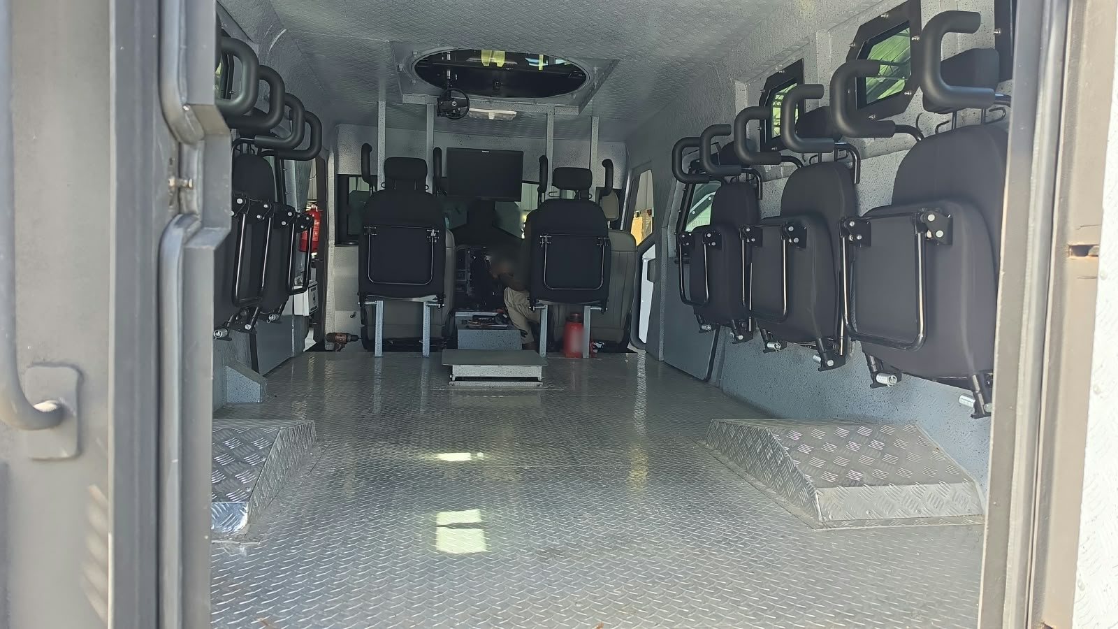 Cabina blindada con asientos abatibles alineados en ambos costados y una escotilla en el techo